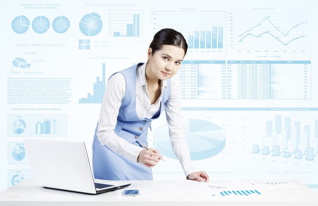 Businesswoman standing at table and writing with pen and infographs at background